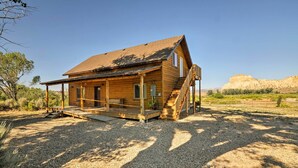 Eine Holzhütte mit Veranda, Treppe und einem Schotterweg.