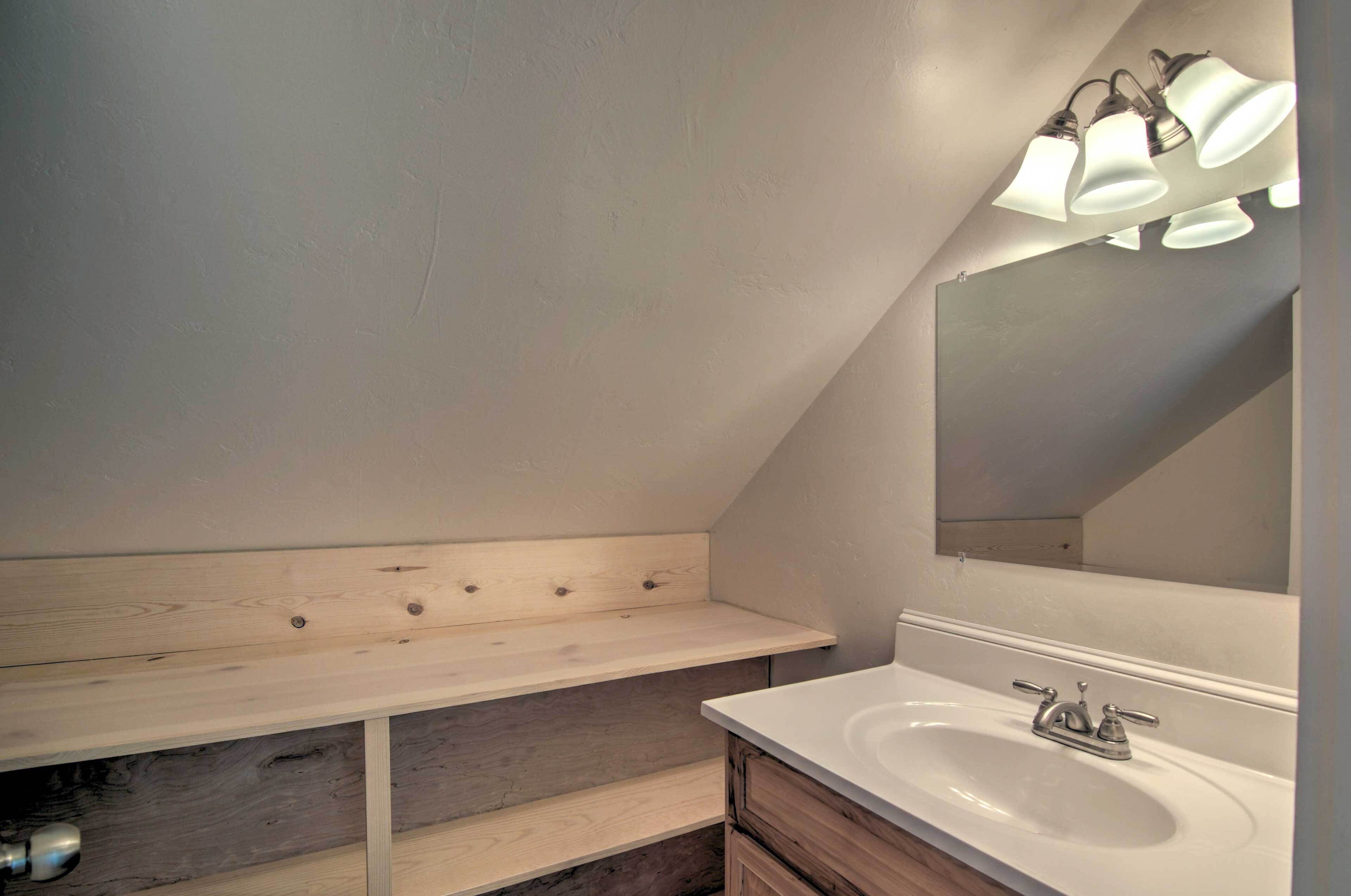 A bathroom with a white sink, wooden vanity, and a mirror.