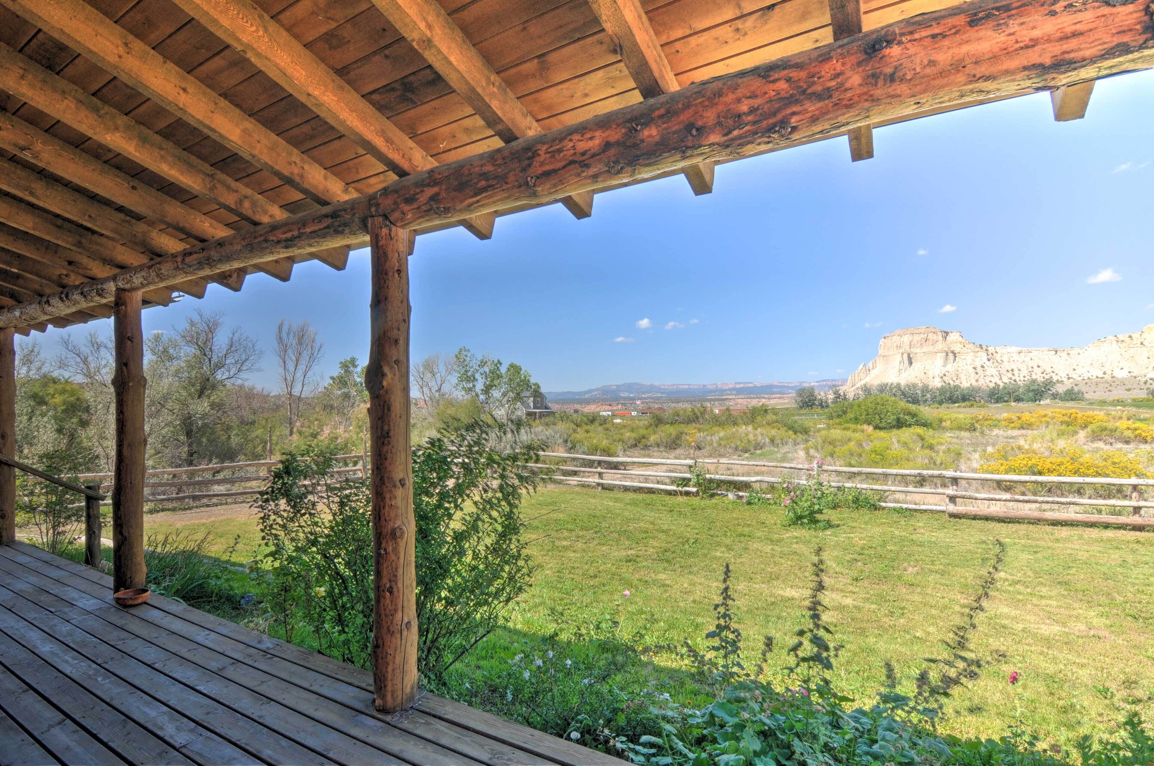 A wooden deck with a view of a grassy field and distant mountains.