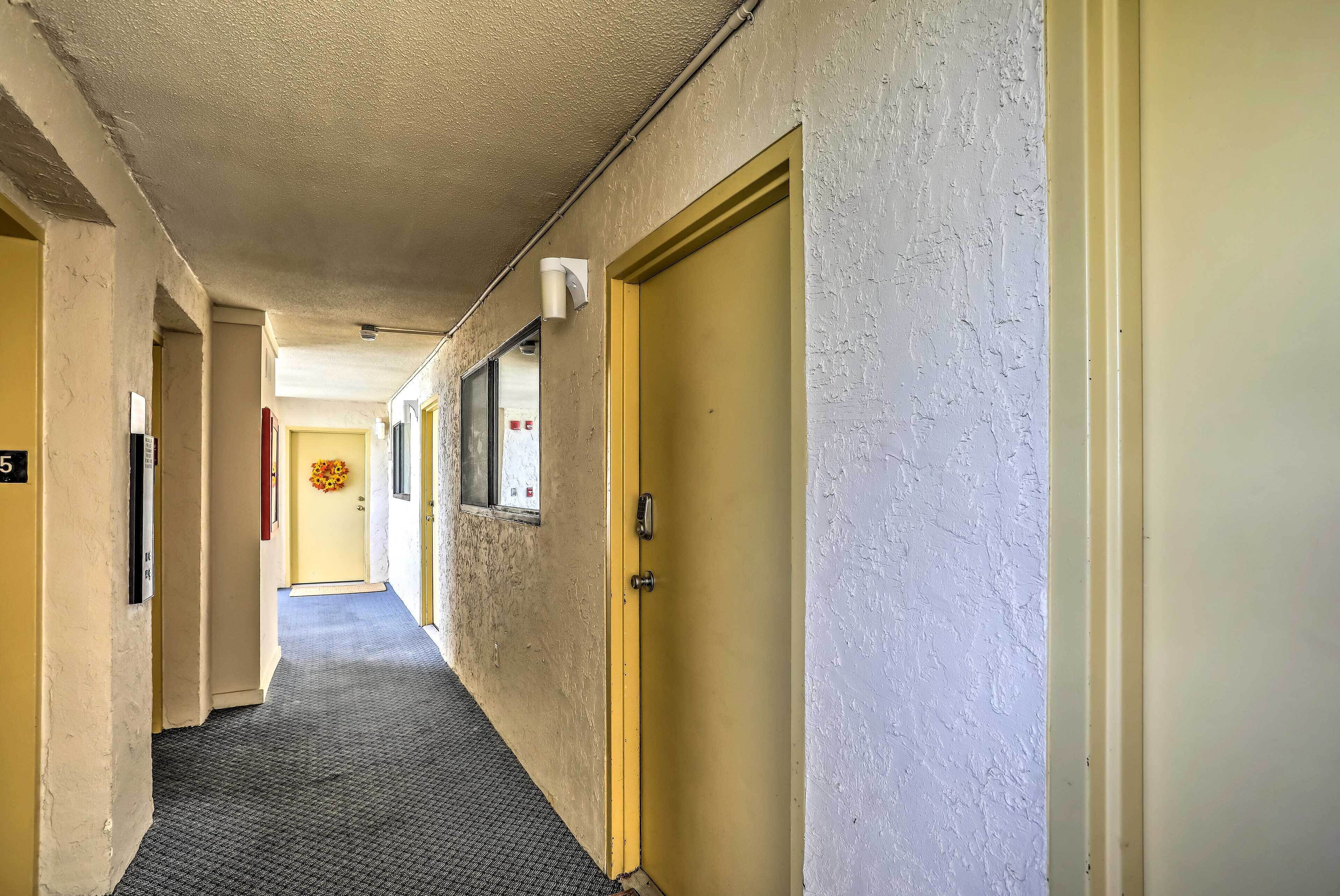 A hallway with doors, a textured wall, and a carpeted floor.