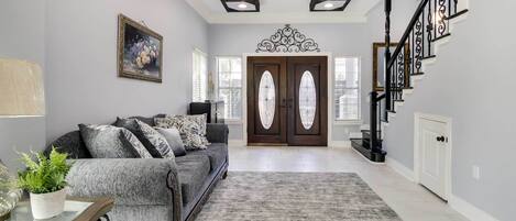 A living room with a gray sofa, a glass coffee table, and a ceiling fan.