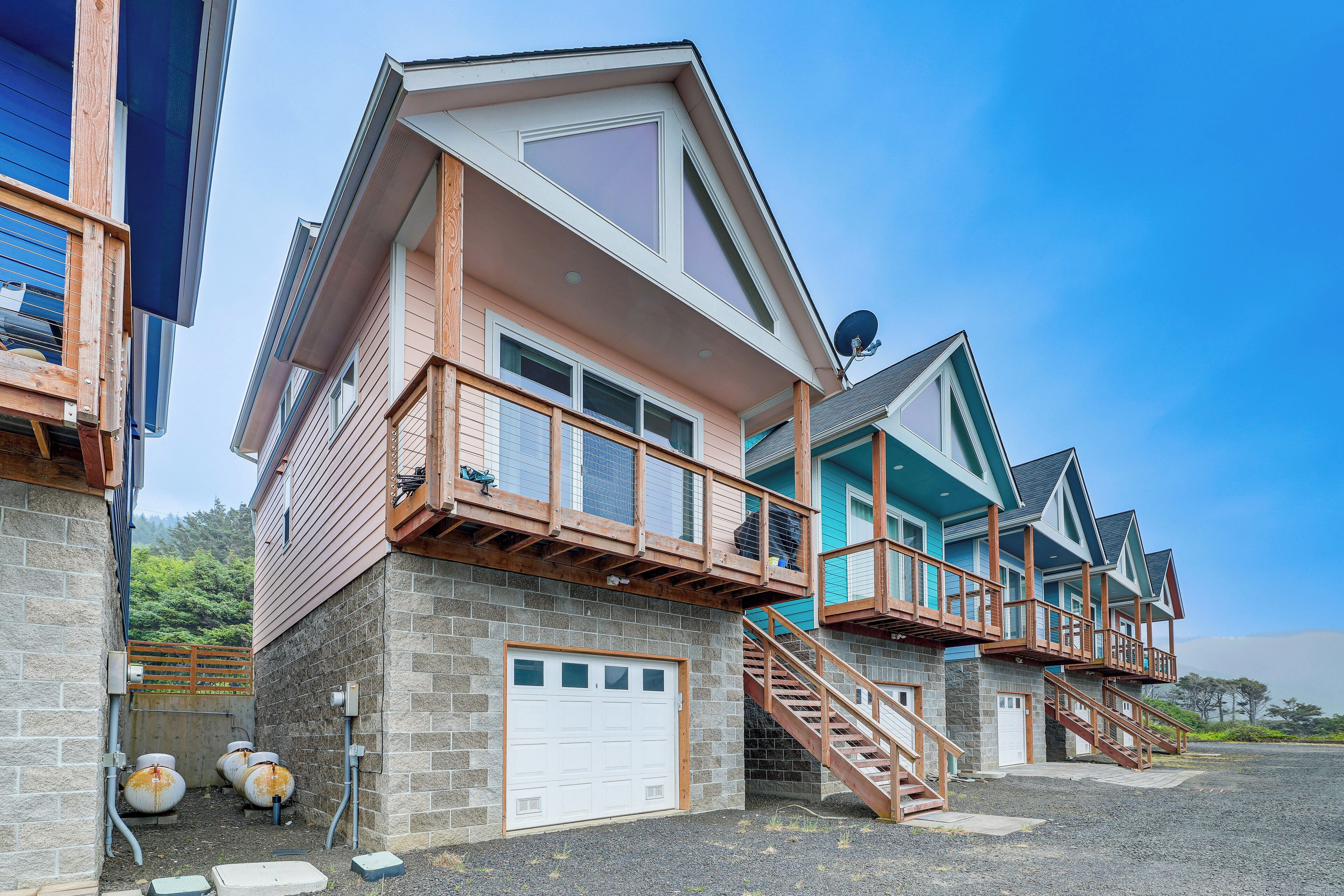 A multi-story residential building with a garage, wooden balconies, and a staircase leading to the upper floors.