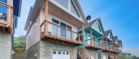 A multi-story residential building with a garage, wooden balconies, and a staircase leading to the upper floors.