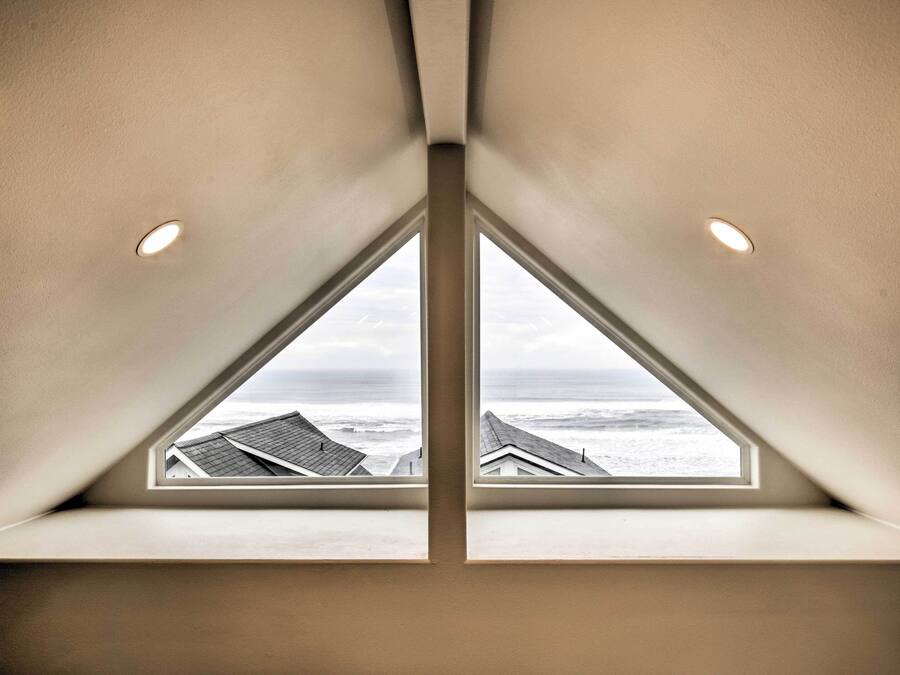 A triangular skylight with a view of the ocean and buildings below.