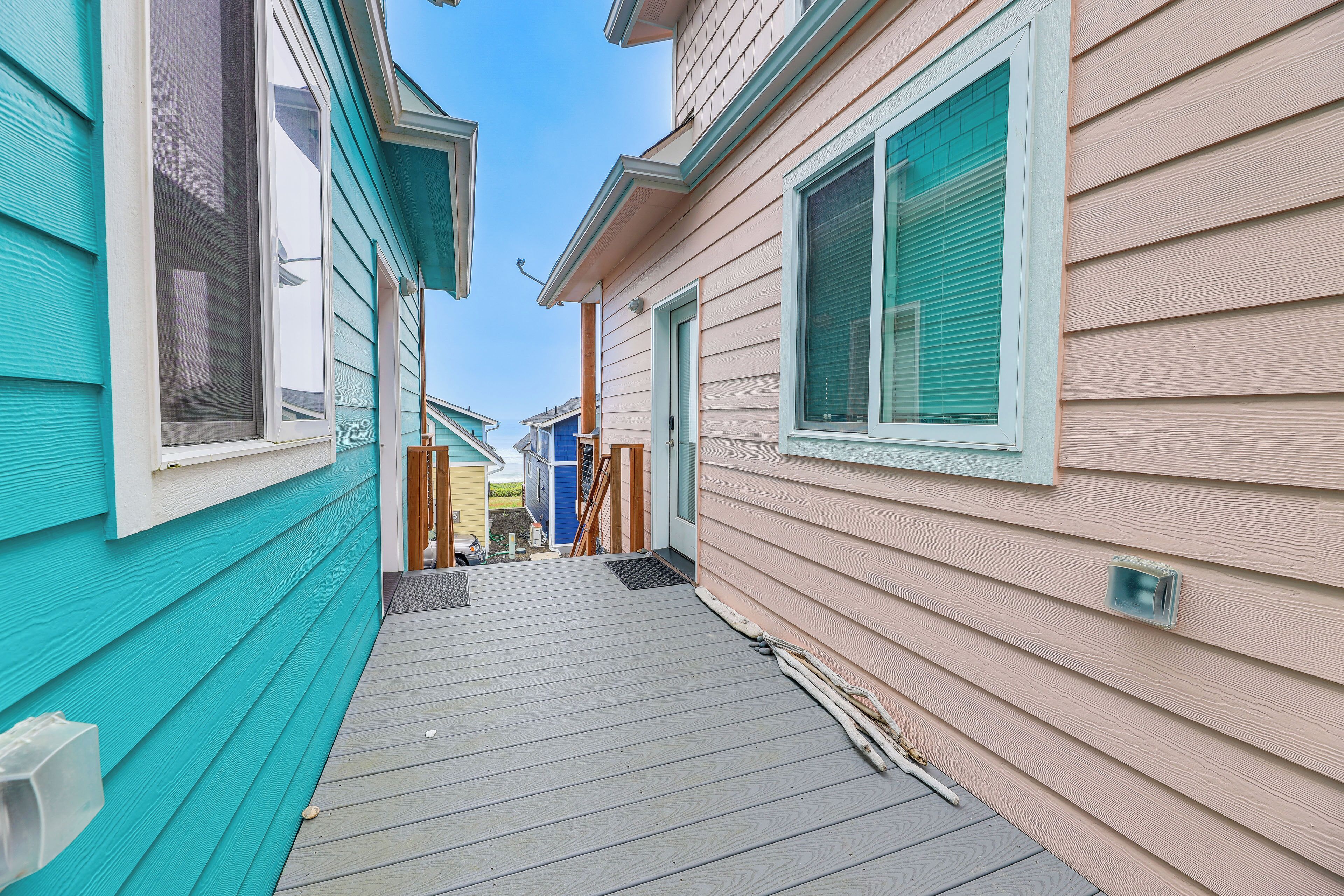 A narrow pathway between two houses with a wooden deck.