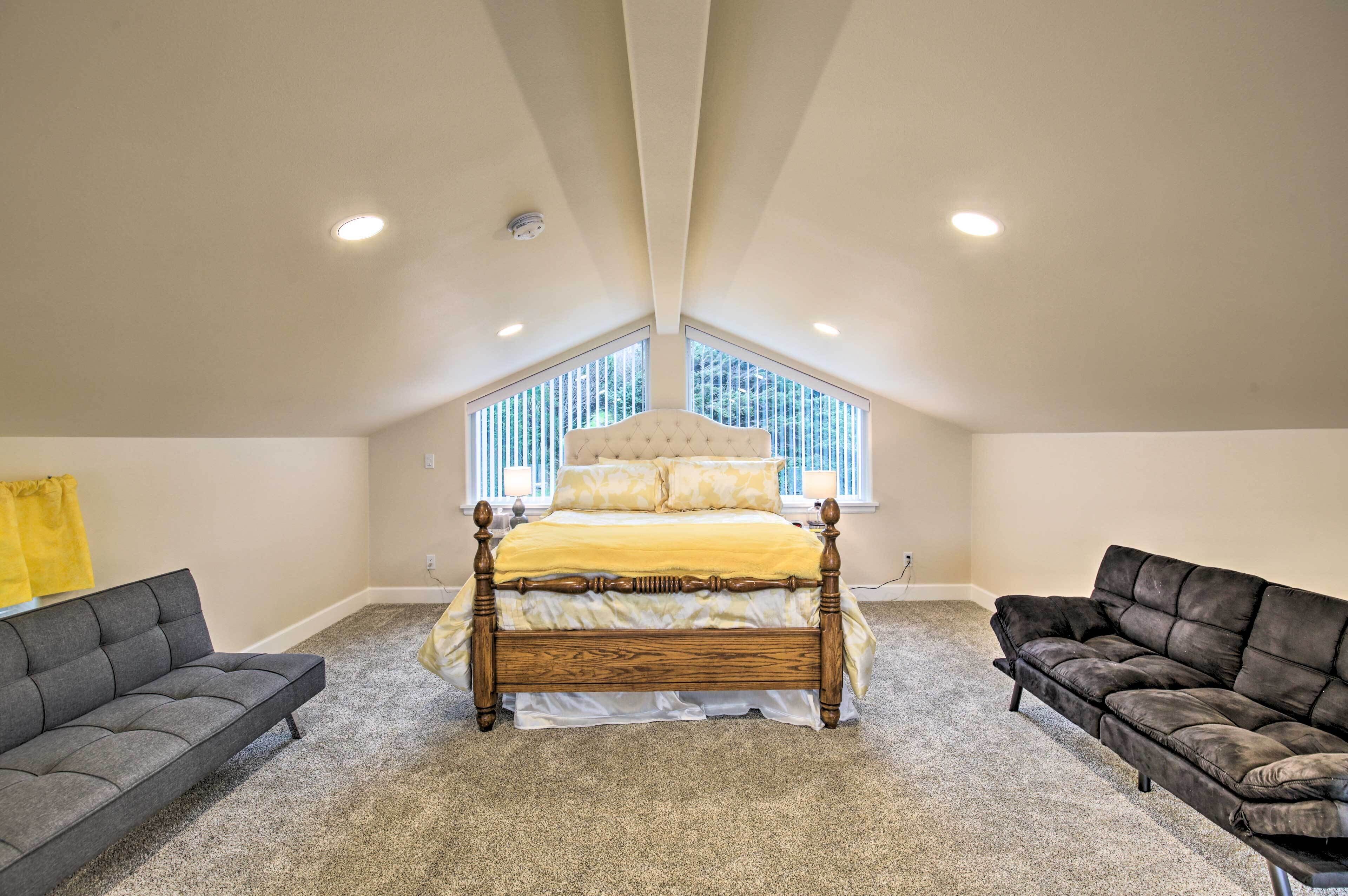 Un dormitorio con una cama de madera, dos sofás y un ventanal grande.