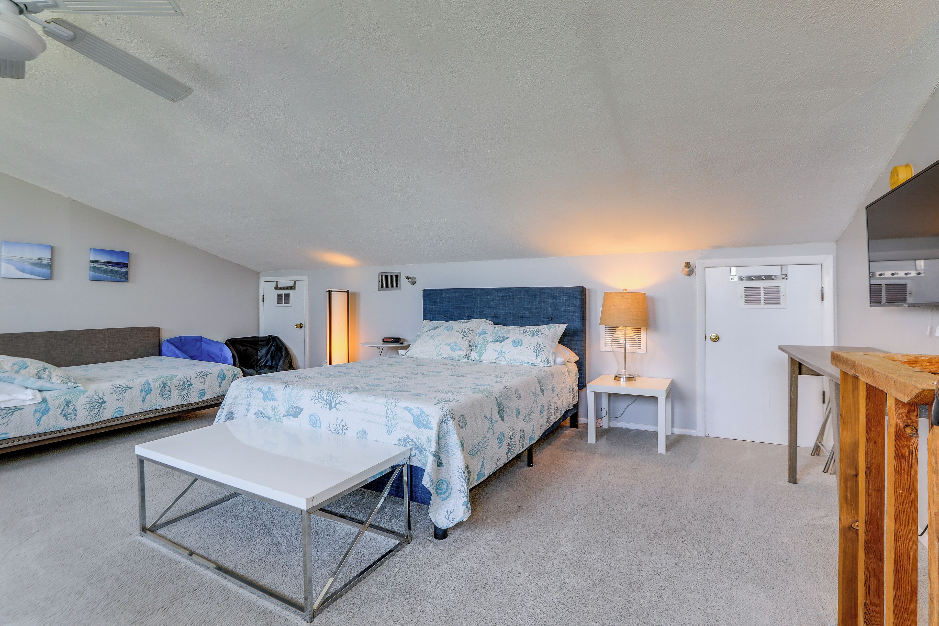 A bedroom with a bed, a bedside table, a chair, and a desk.