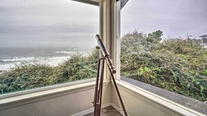 A telescope positioned by a window overlooking the ocean.