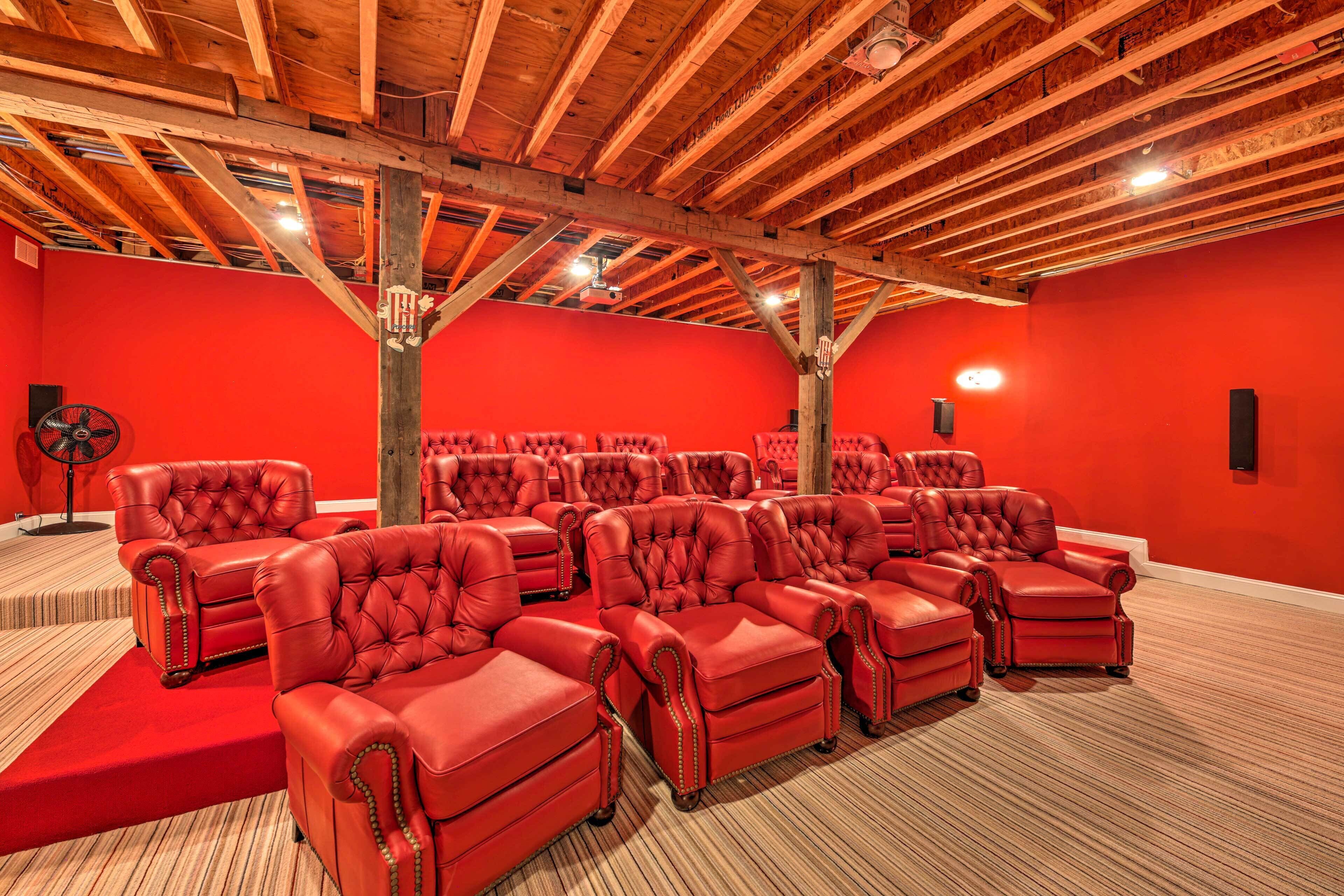 A room with multiple red leather sofas arranged in rows, a wooden ceiling with exposed beams, and a red carpeted floor.