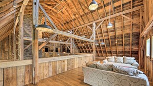 Una habitación rústica en el ático con vigas de madera a la vista, suelo de madera y una cama con ropa de cama estampada.