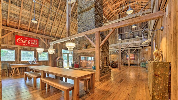 Interior rústico de madera con una gran mesa de madera y bancos, un letrero de Coca-Cola, candelabros y una chimenea de piedra.