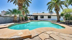 A swimming pool with a stone deck, surrounded by palm trees and a house with a covered patio. - Yuma Vacation Rental w/ Private Pool & Patio! (Yuma)