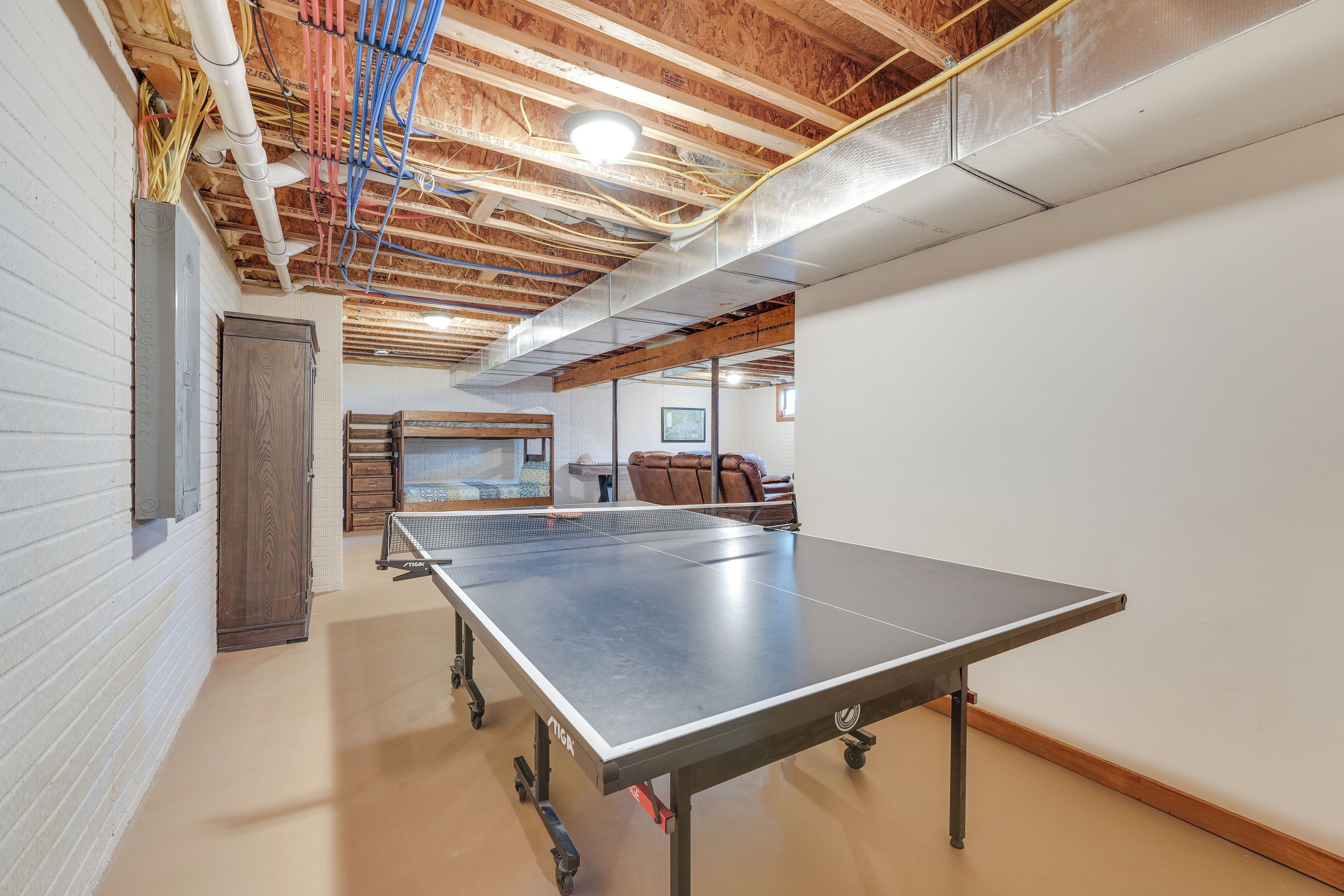 Une table de ping-pong dans une pièce aux poutres apparentes et aux murs blancs.