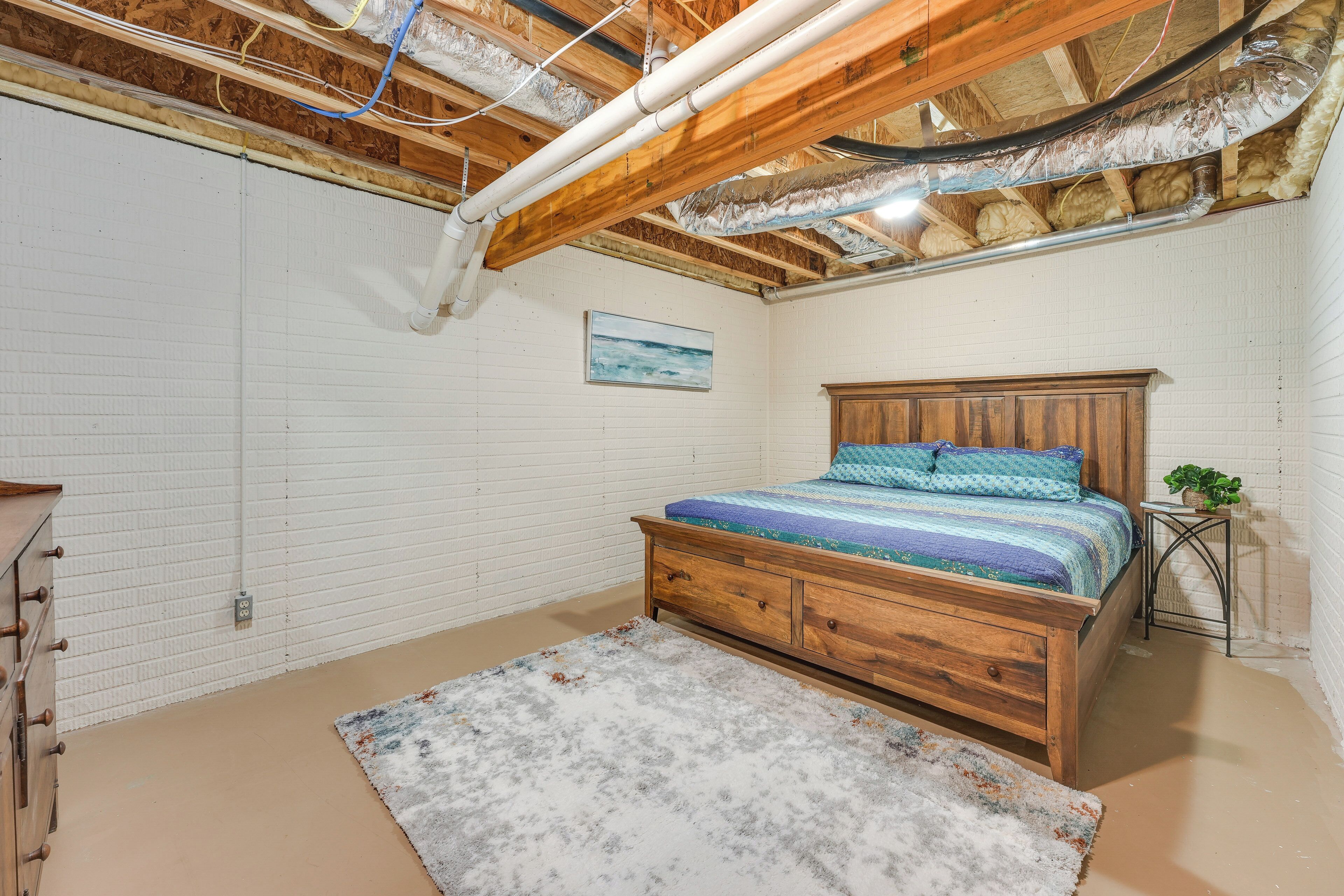 A bedroom with a wooden bed, a dresser, and a radiator on the wall.