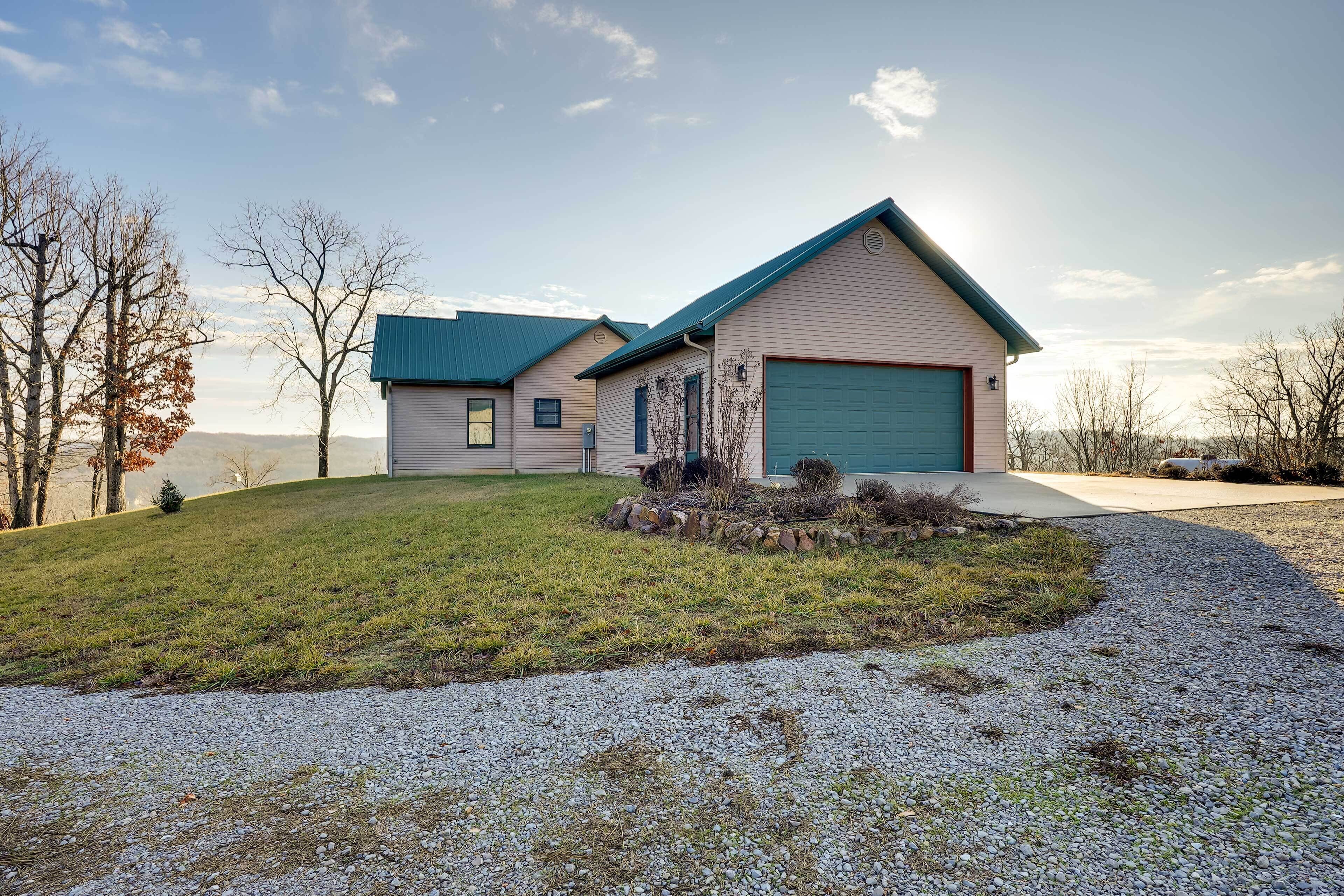 A single-story house with a green roof, a garage, and a well-maintained lawn.