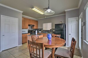 A kitchen with wooden cabinets, a round dining table, and a blue pitcher. - Houston Family Home w/ Yard ~ 8 Mi to NRG Stadium! (Houston)