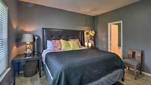 A neatly arranged bedroom with a large bed, bedside lamps, and a chair.