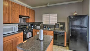 A kitchen with wooden cabinets, a black refrigerator, a microwave, a stove, and a dishwasher.