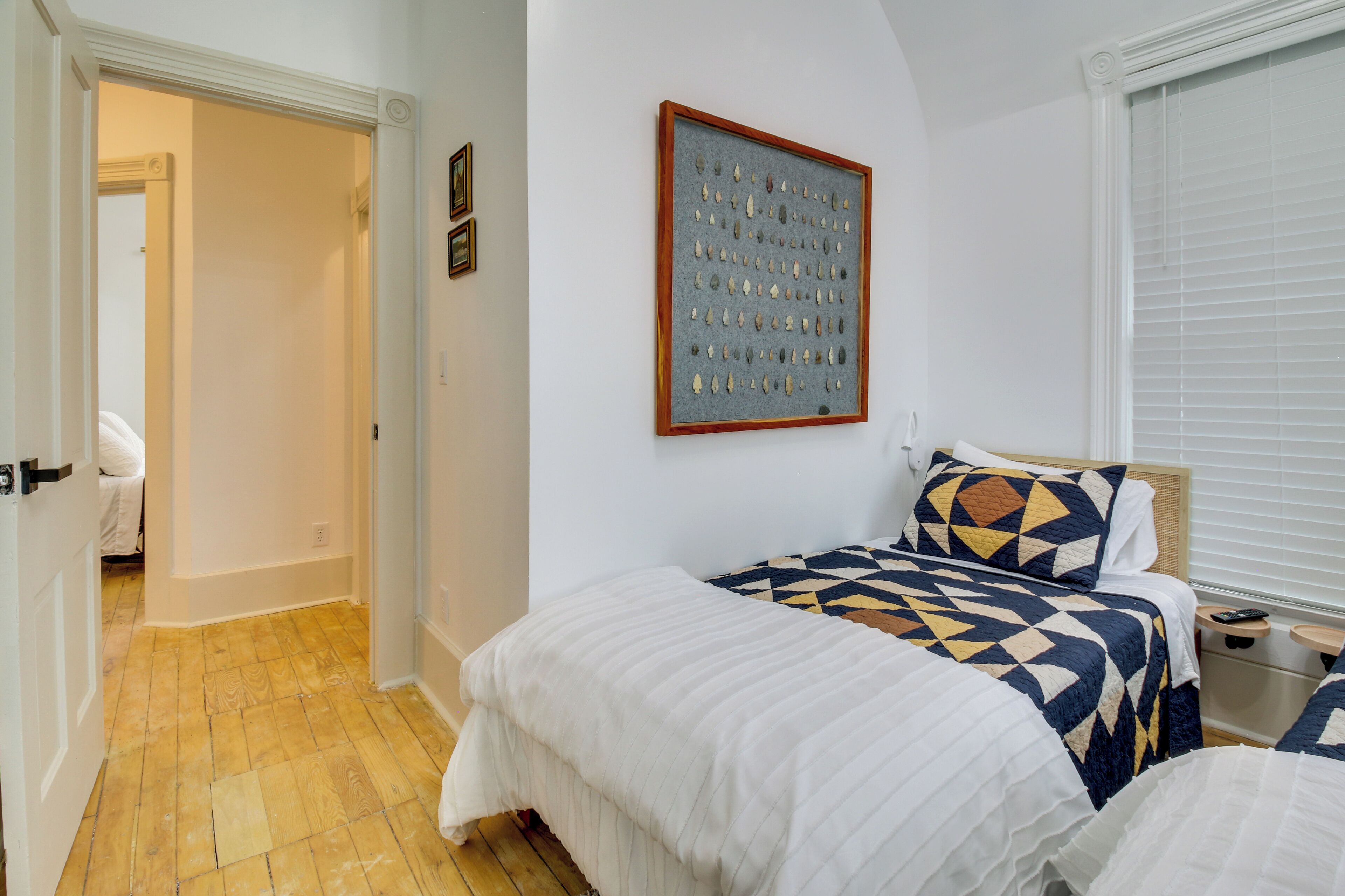 A bedroom with two beds, a framed picture on the wall, and a wooden floor.