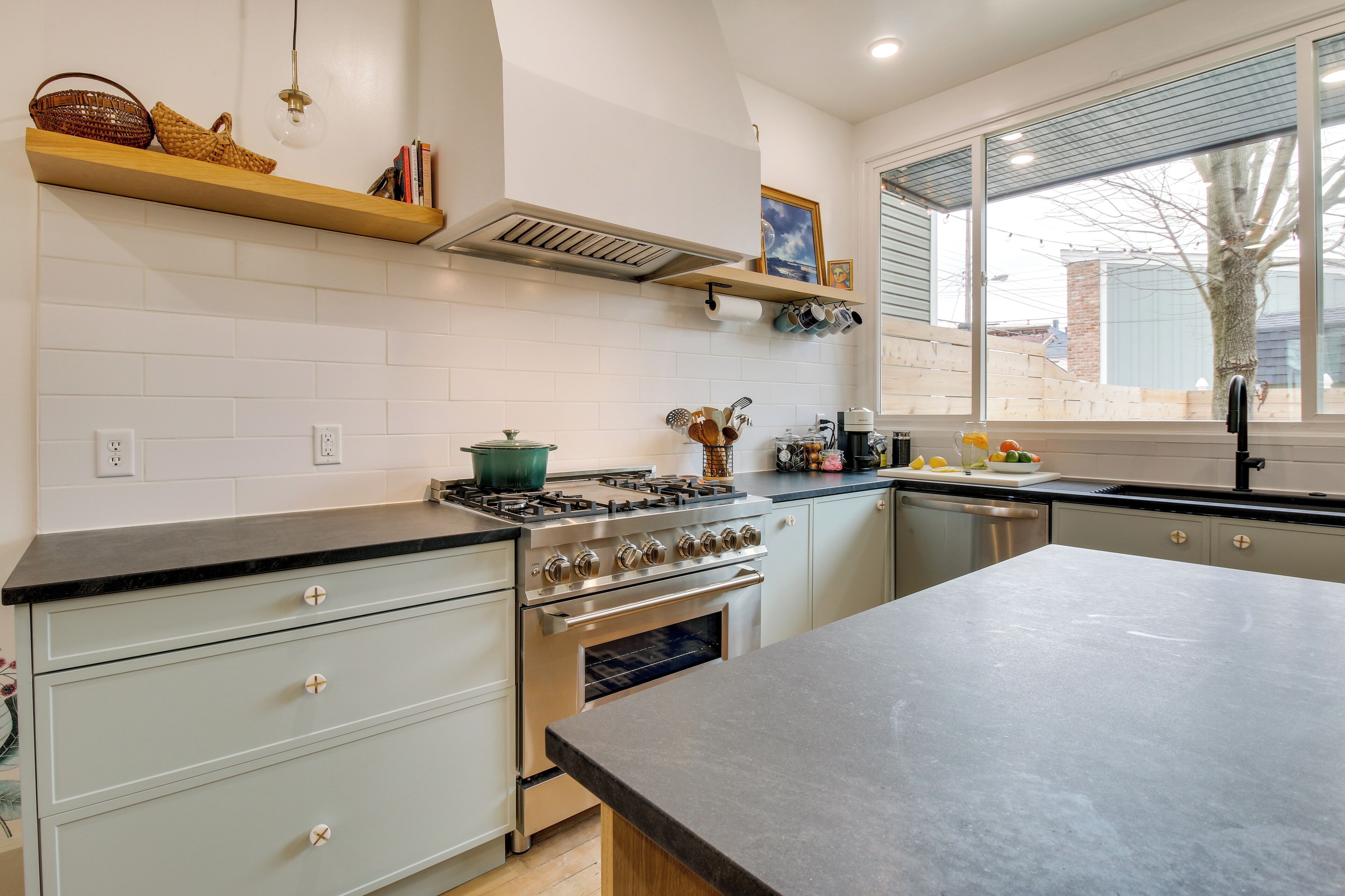 A modern kitchen with white cabinets, a large island, and a window with a view of the outside.