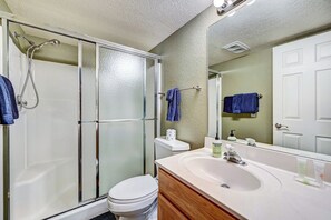 A bathroom with a glass-enclosed shower, a white toilet, a sink with a mirror, and two towels hanging on a rack. - Flagstaff Condo w/ Balcony in Golf Community! (Flagstaff)