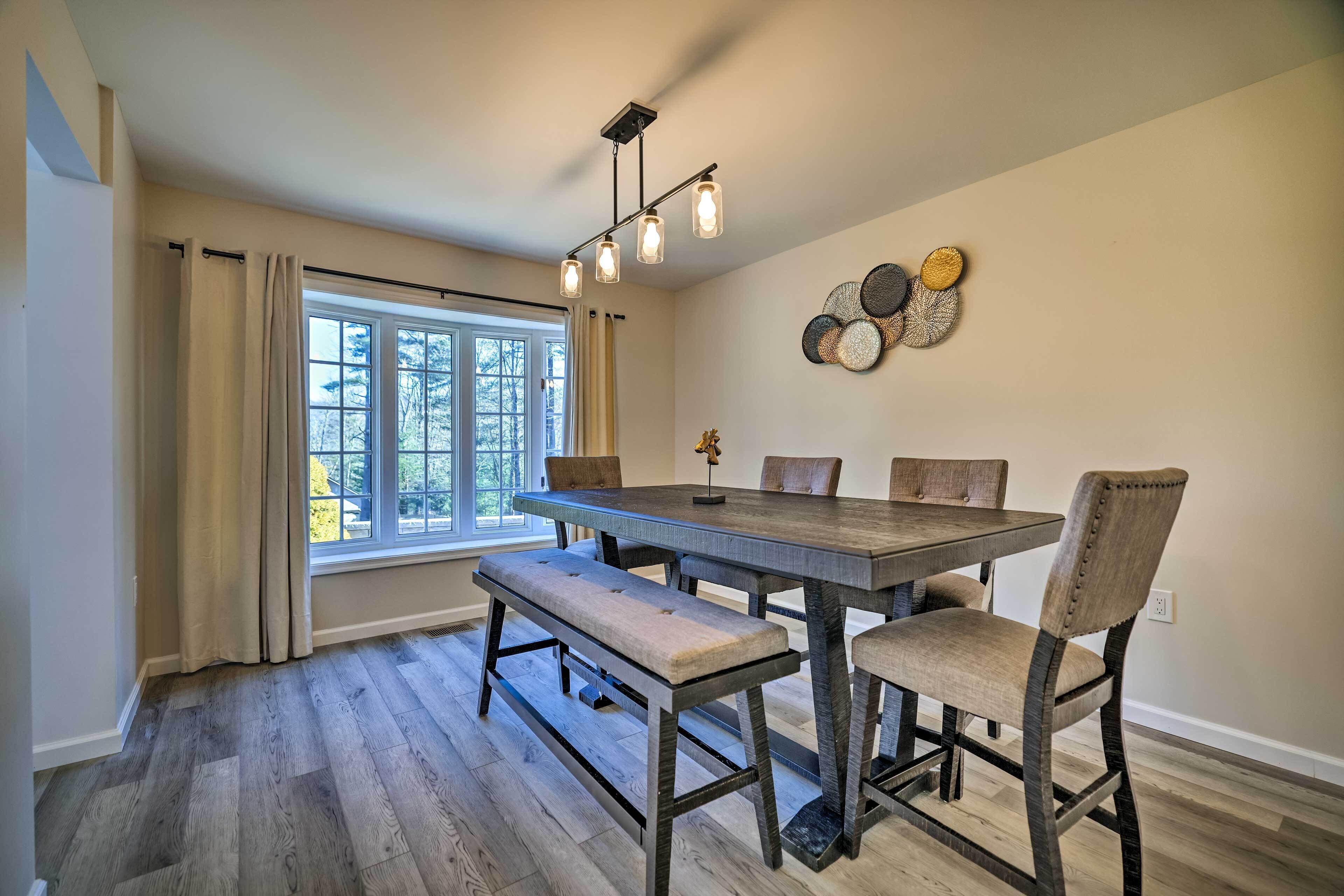 A dining area with a wooden table and benches, a chandelier, and decorative wall art.