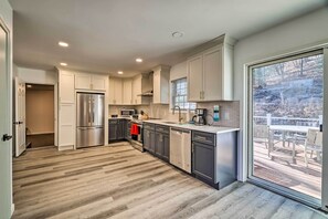 Una cocina moderna con electrodomésticos de acero inoxidable, lavavajillas y un amplio ventanal con vistas a una terraza.