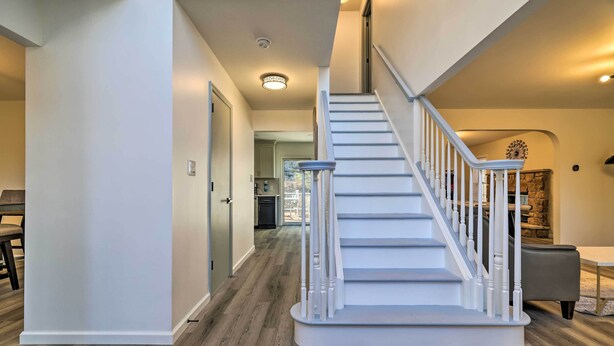 A staircase with white railings and a wooden floor leading to a kitchen area. - Movie Room, Hot Tub: Pocono Vacation Rental! (East Stroudsburg)