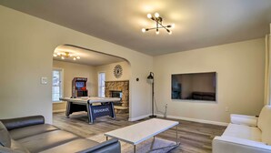 A living room with a pool table, leather sofas, a white coffee table, and a stone fireplace. - Movie Room, Hot Tub: Pocono Vacation Rental! (East Stroudsburg)