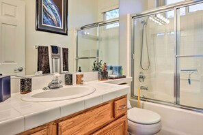 A bathroom with a double sink, wooden vanity, a glass shower enclosure, and a toilet. - Palm Desert Vacation Rental w/ Private Pool! (Palm Desert)