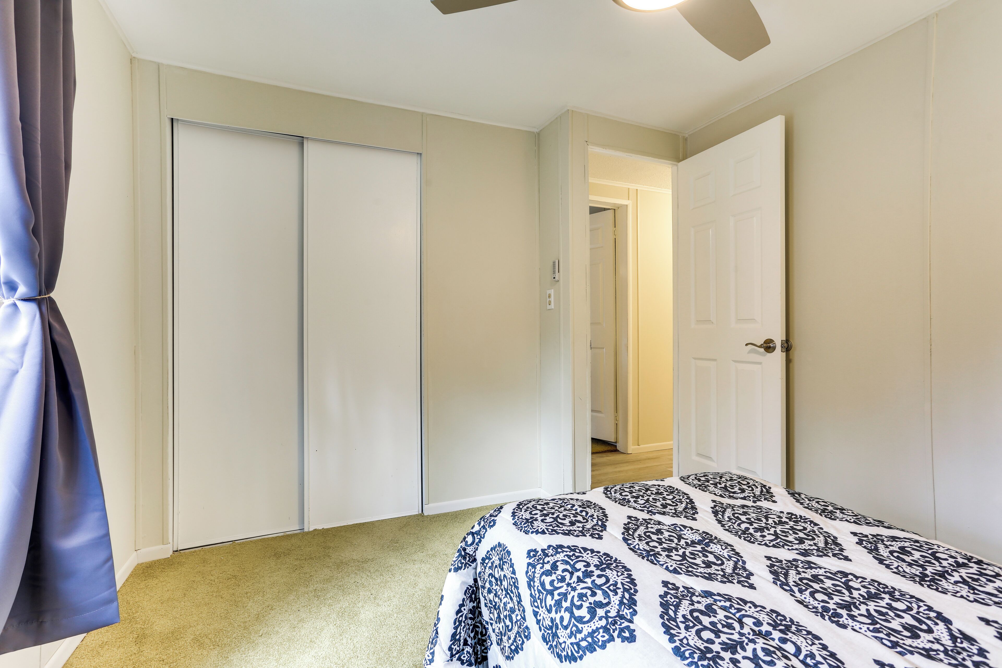 A bedroom with a bed, a closet, and a door leading to another room.