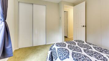A bedroom with a bed, a closet, and a door leading to another room.
