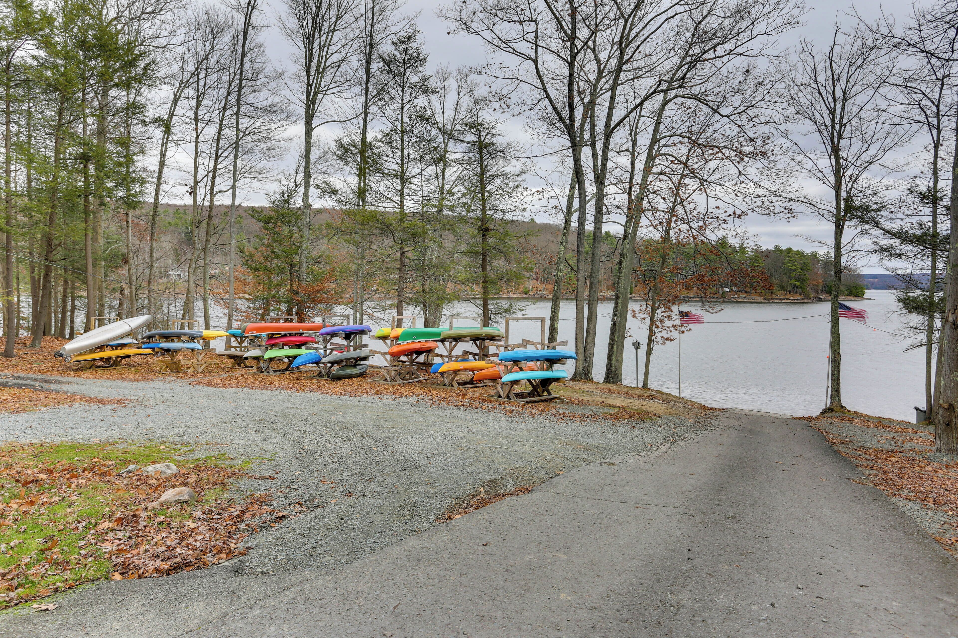 A gravel path leading to a dock with colorful kayaks and a rowboat.