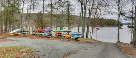 A gravel path leading to a dock with colorful kayaks and a rowboat.