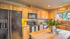 A modern kitchen with wooden cabinets, stainless steel appliances, and a wooden dining table.