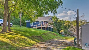 A house with a covered porch, a driveway, and a grassy hill. - Quaint Cottage Overlooking Cherokee Reservoir (Bean Station)