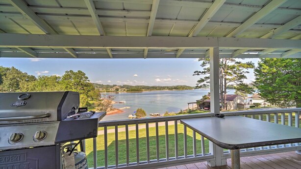 A covered deck with a grill and a gas tank, overlooking a lake with boats and houses in the background. - Quaint Cottage Overlooking Cherokee Reservoir (Bean Station)