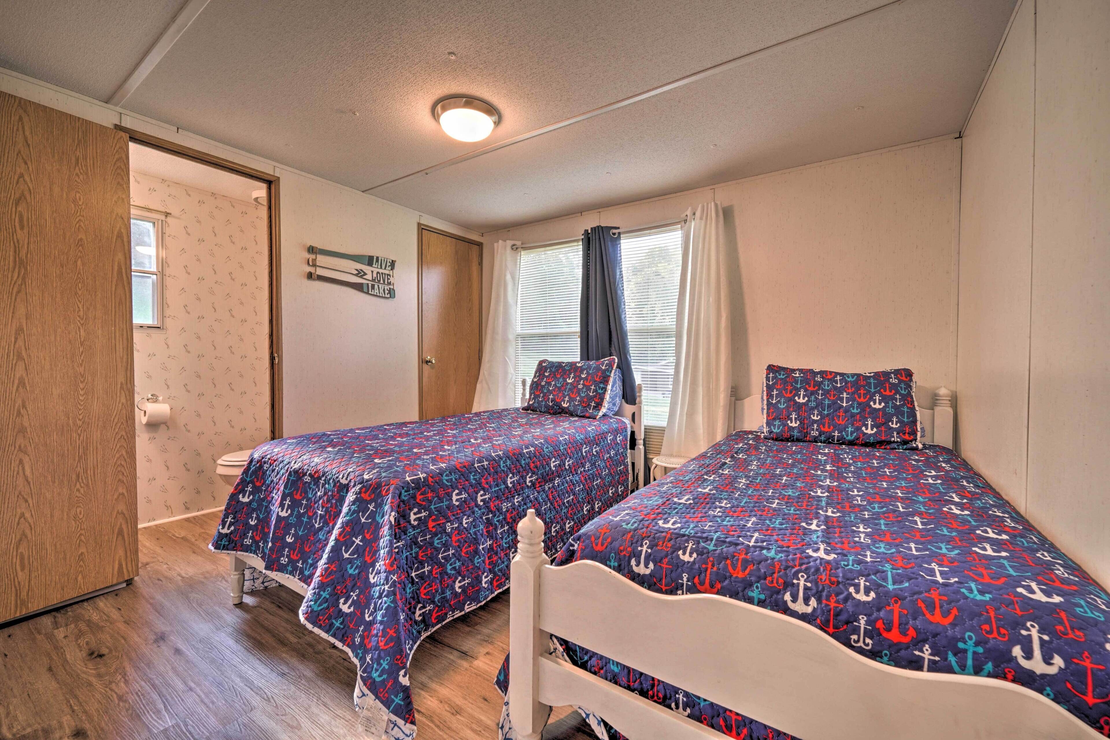 Une chambre avec deux lits, un plancher en bois, une fenêtre avec des rideaux et une porte.