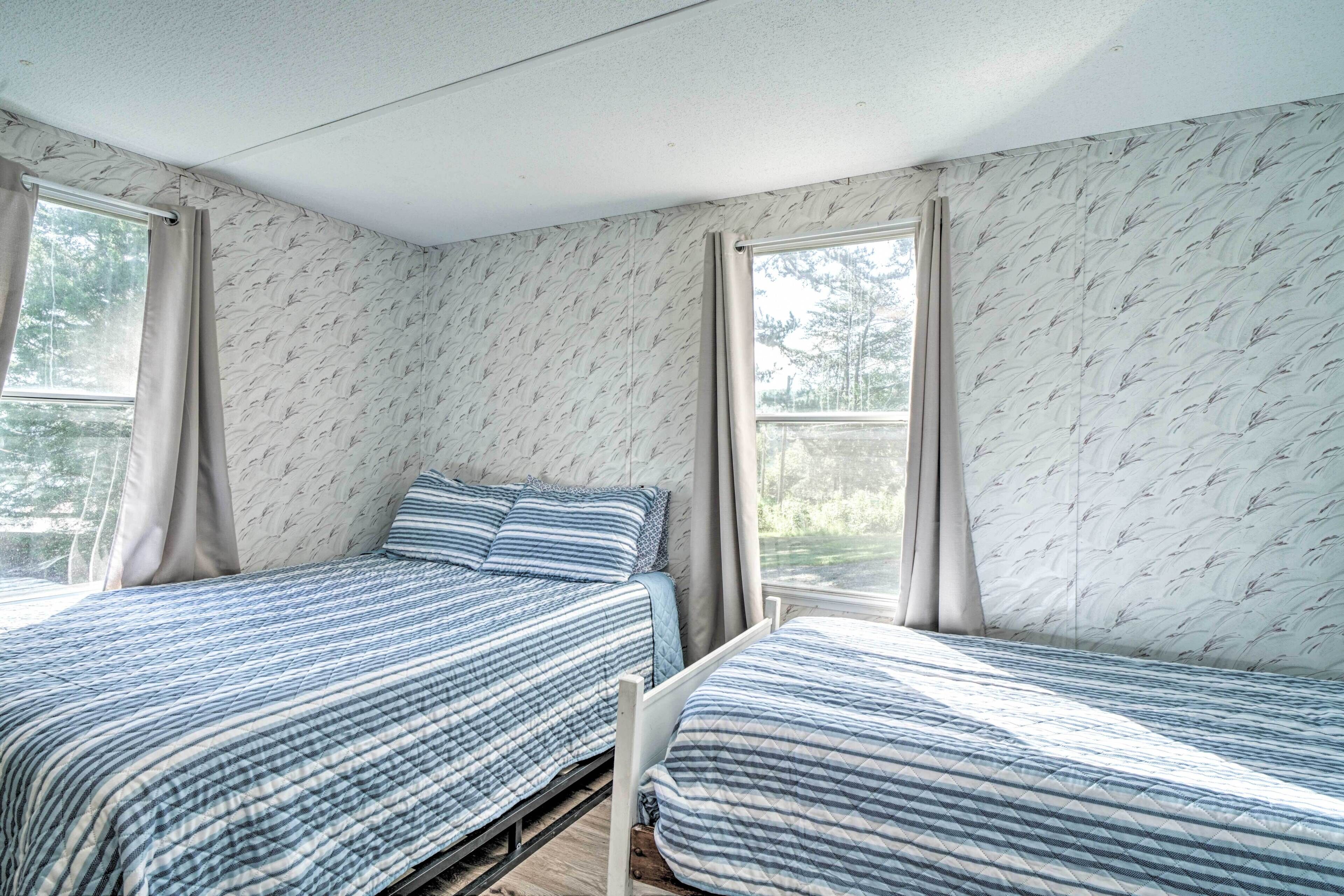 Un dormitorio con dos camas, una ventana y un papel tapiz estampado.