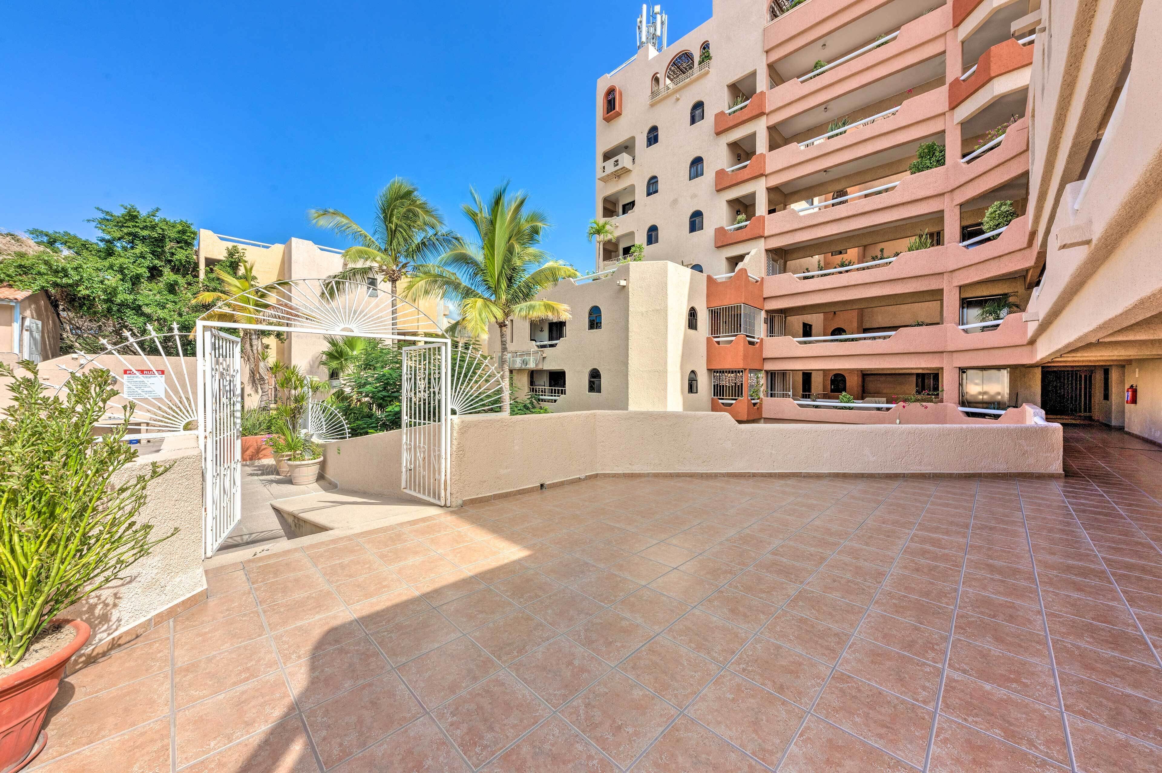 A multi-story building with balconies, a gated entrance, and potted plants.
