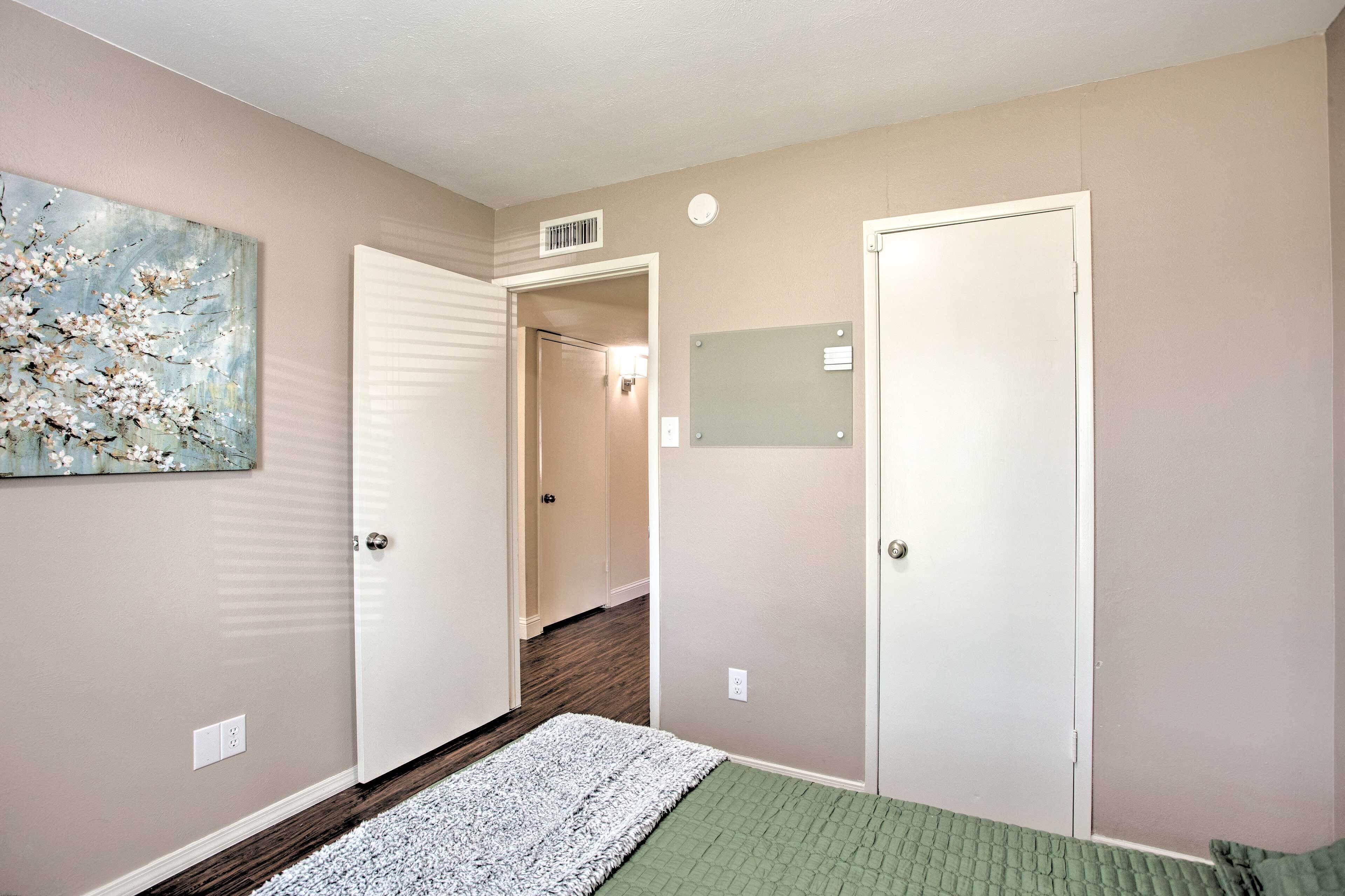 A bedroom with a bed, a door, a hallway, and a painting on the wall.