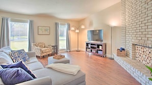 A living room with a sofa, armchair, and a TV stand.