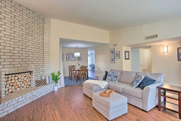 A living room with a brick fireplace, a gray sofa, and a wooden coffee table.