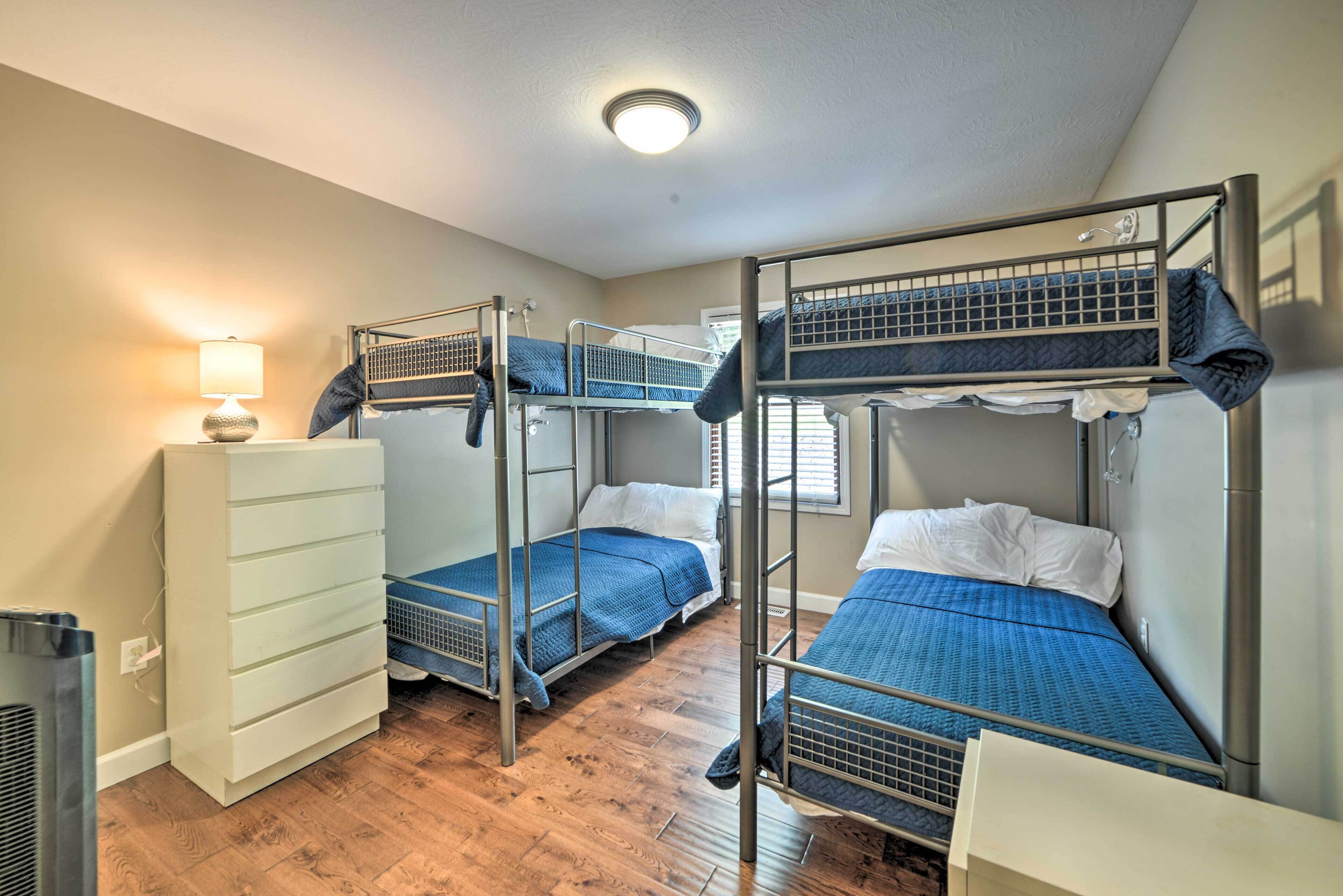 Une chambre de dortoir avec des lits superposés, une commode blanche et une lampe.