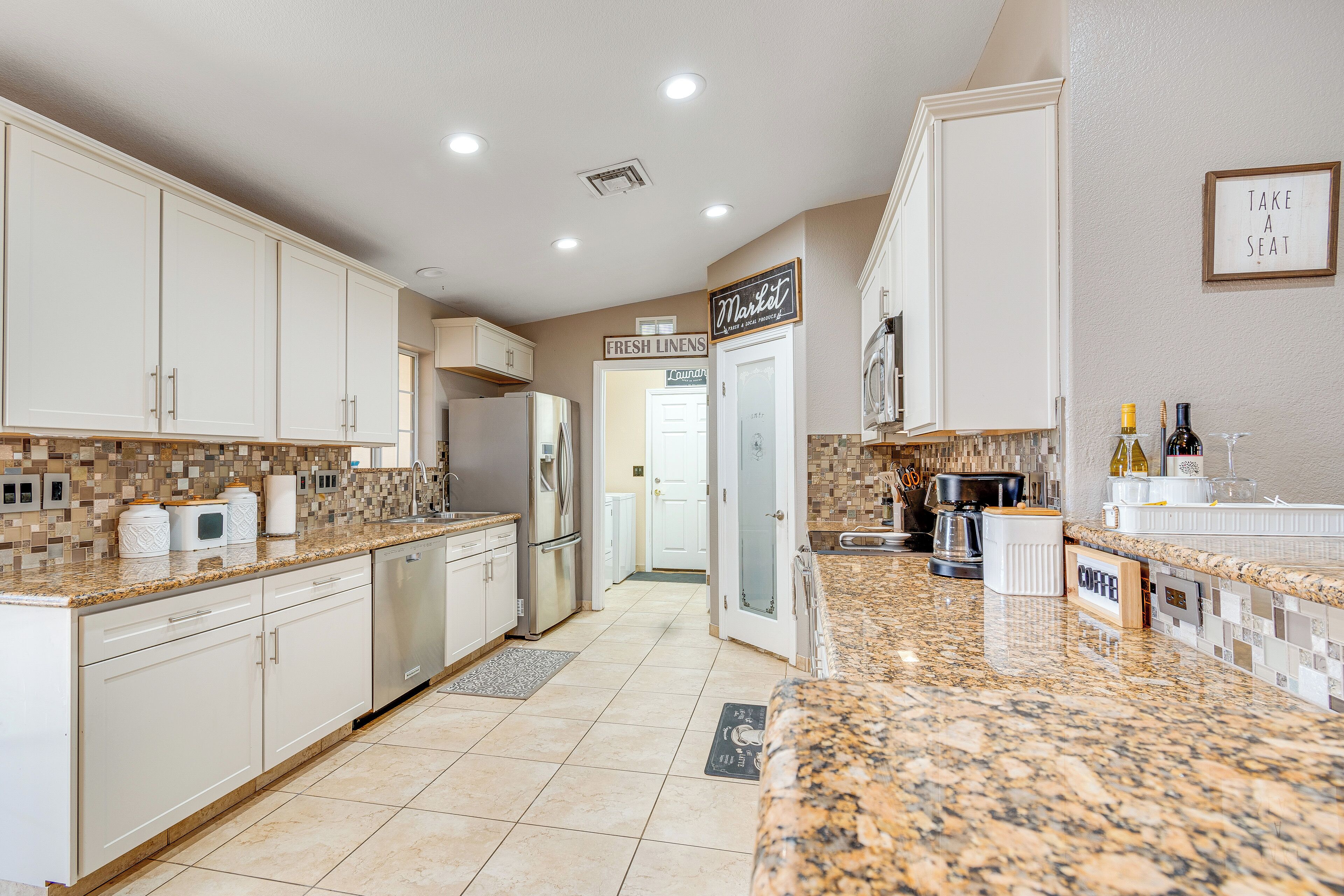 A modern kitchen with white cabinets, granite countertops, and a sign that reads 'Market.'