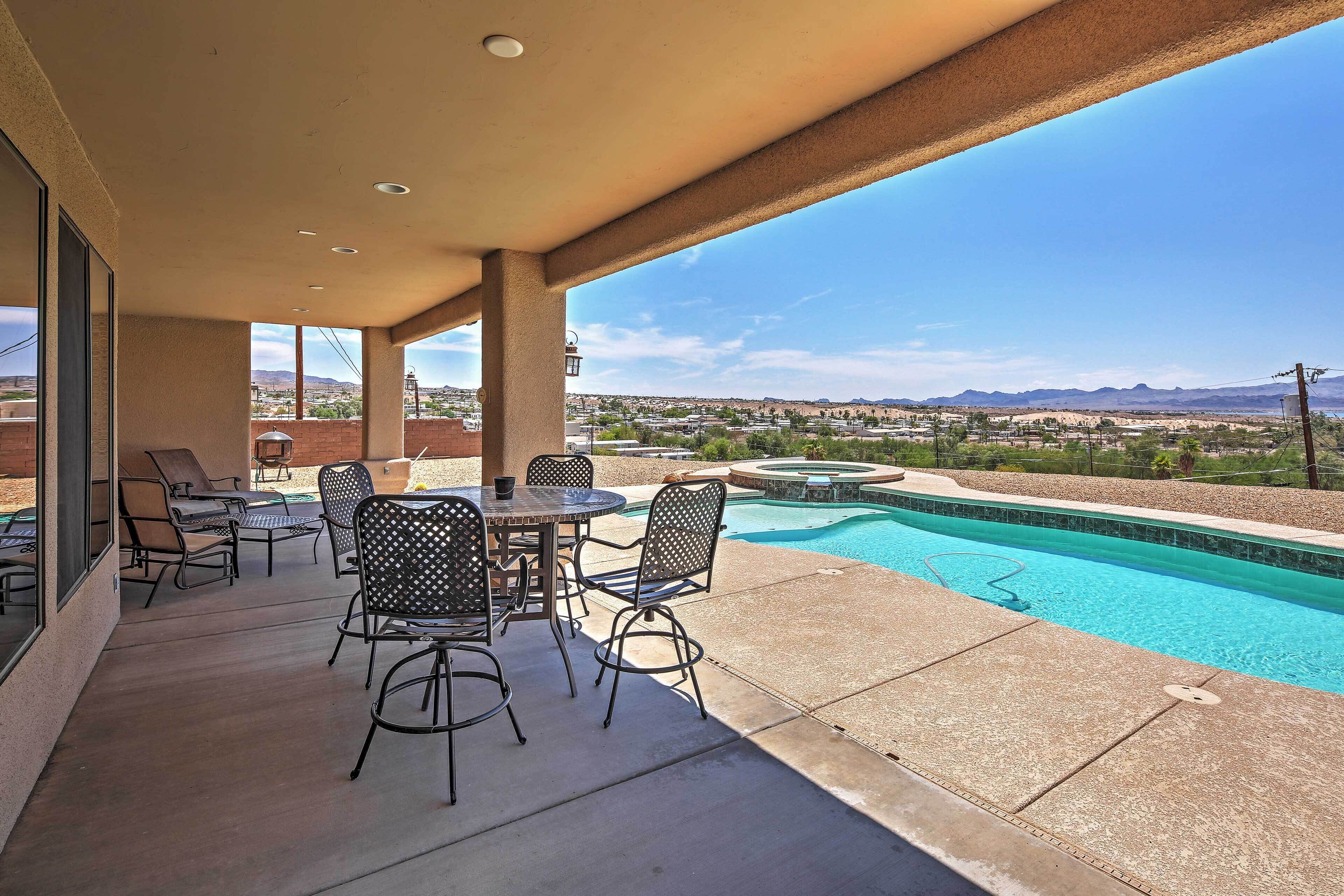 An outdoor patio with a pool, seating area, and a view of the surrounding landscape.