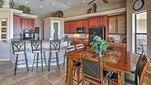 A spacious kitchen with wooden cabinets, a large island with bar stools, a dining table with chairs, and a ceiling fan. - Private Pool: Mtn-view Lake Havasu City Retreat (Lake Havasu City)
