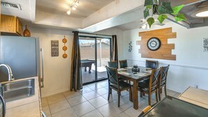 A modern kitchen with a dining area, a clock on the wall, and a view to the outside.
