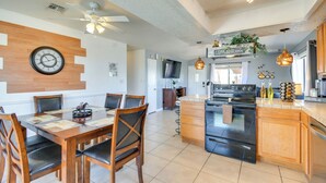 A modern kitchen with a central island, wooden cabinetry, and a dining area with a round table and chairs.