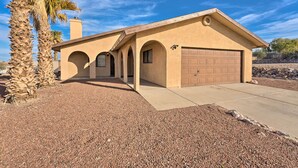 A single-story house with a garage, arched entryway, and a gravel driveway.